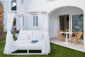 a white bed on a patio with a table at FERGUS Style Carema Beach in Cala en Bosc