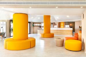 un vestíbulo con columnas amarillas y sillas naranjas en Tagoro Family & Fun Costa Adeje en Adeje