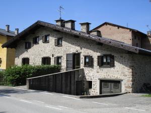an old stone building with a fence next to a street at Casa Margherita in Baselga di Pinè