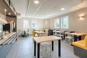 une salle à manger avec des tables et des chaises dans un restaurant dans l'établissement B&B HOTEL Aix-en-Provence Pont de l'Arc, à Aix-en-Provence
