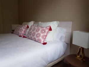 Una cama con almohadas rojas y blancas y una lámpara. en Apartamentos La Senda de Llanes, en Llanes