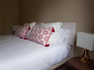 a bed with red and white pillows and a lamp at Apartamentos La Senda de Llanes in Llanes