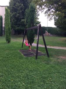 Una joven sentada en un columpio en un parque en Locazione turistica Isabella en Castelnuovo del Garda
