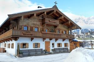 a large wooden building with a balcony in the snow at Haus Strobler in Going