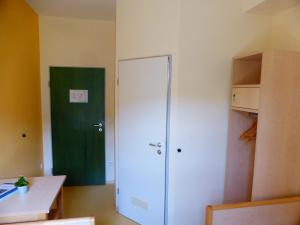 Zimmer mit einem weißen Schrank und einer grünen Tür in der Unterkunft Campus Prackenfels in Altdorf bei Nürnberg