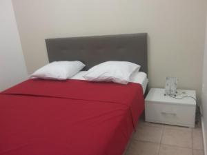 uma cama com um cobertor vermelho e almofadas brancas em GÎTE MORINGA em Bouillante
