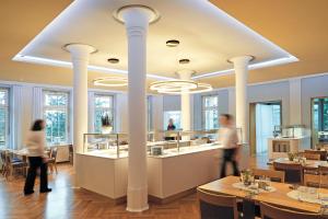 two people walking around a restaurant with columns at Schönblick - Christliches Gästezentrum in Schwäbisch Gmünd