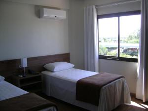a hotel room with two beds and a window at Hotel Areias Brancas in Rosário do Sul