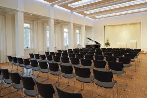 una sala conferenze con sedie e pianoforte a coda di Schönblick. Christliches Gästezentrum a Schwäbisch Gmünd