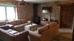 a living room with two couches and a tv at Casa Rural Rojo del Tietar in La Iglesuela