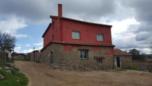 an old stone house with a red roof on a dirt road at Casa Rural Rojo del Tietar in La Iglesuela