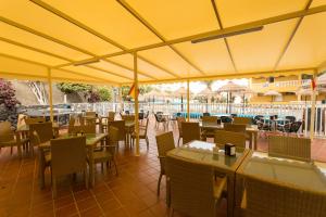 a restaurant with tables and chairs and a yellow umbrella at El Marques Palace by Intercorp Group in Puerto de Santiago