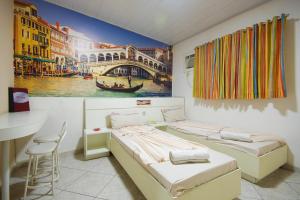 two beds in a room with a painting on the wall at Mirage Motel Guarulhos in São Paulo