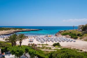 a beach with a lot of umbrellas and the ocean at FERGUS Style Carema Beach in Cala en Bosc