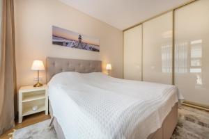 1 dormitorio con 1 cama blanca grande y paredes de cristal en Simpsono Apartamentai Nr.1, en Palanga