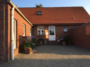 a brick house with a dog sitting in front of it at Minsener Warft in Wangerland