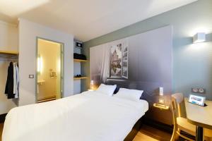 ナントにあるB&B HOTEL Nantes Parc Expos La Beaujoireのベッドルーム(白い大型ベッド1台、デスク付)