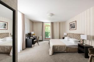 a hotel room with two beds and a mirror at Amberton Cathedral Square Hotel Vilnius in Vilnius