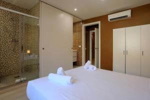a bedroom with a white bed and a glass shower at BBarcelona Còrsega Flats in Barcelona