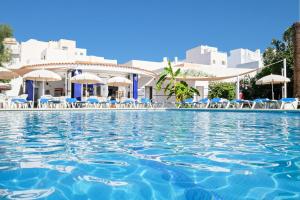 a swimming pool at a resort with chairs and umbrellas at azuLine Hotel Llevant in San Antonio