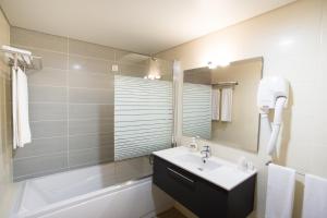 
a bathroom with a sink, shower, and tub at Antillia Hotel in Ponta Delgada
