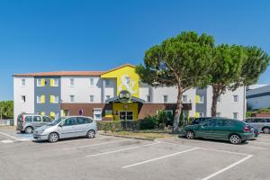 un parking avec des voitures garées devant un bâtiment dans l'établissement B&B HOTEL Marseille Estaque, à Marseille