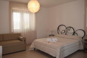 a bedroom with a bed and a chair and a chandelier at Masseria Corte Masseriola in Alberobello