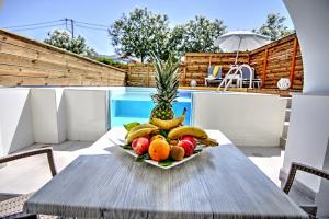 een fruitschaal op een tafel naast een zwembad bij Klelia Beach Hotel by Zante Plaza in Kalamaki