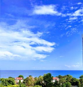 un cielo azul y el océano con casas y árboles en Sara Sea View Olimp, en Olimp