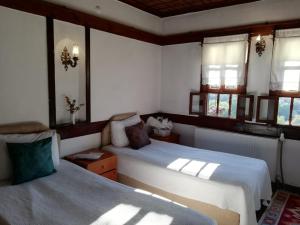 1 dormitorio con 2 camas y 2 ventanas en Turgut Reis Konak en Safranbolu