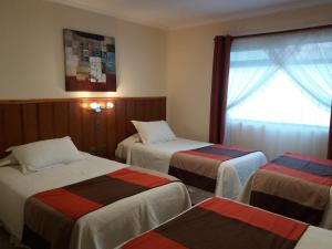 a hotel room with three beds and a window at Gran Hotel Ovalle in Ovalle