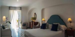 a bedroom with a large bed with blue pillows at Hotel Montemare in Positano