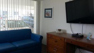 a living room with a blue couch and a flat screen tv at Tide Winds Motel in Wildwood
