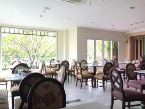 a dining room with tables and chairs and windows at Kitlada Hotel Udonthani in Udon Thani