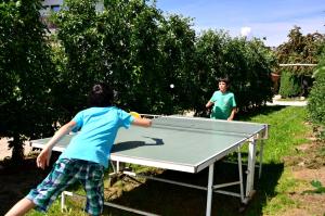 2 bambini che giocano a ping pong su un tavolo da ping pong di Ferienwohnung Pippohof ad Appiano sulla Strada del Vino