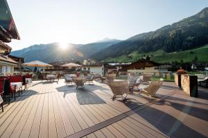 a deck with chairs and tables with mountains in the background at Premium Activehotel Bergkönig in Neustift im Stubaital