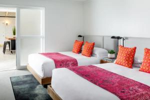 two beds in a hotel room with red pillows at Bluebird Spa City Motor Lodge in Saratoga Springs