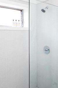 a bathroom with a shower with white tile at Bluebird Spa City Motor Lodge in Saratoga Springs +41 photos