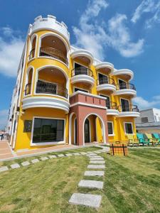 a yellow and white building with a grass yard at Shi Guang Sea View in Magong