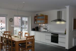 uma cozinha com uma mesa e uma cozinha com armários brancos em Nordseestrand em Horumersiel
