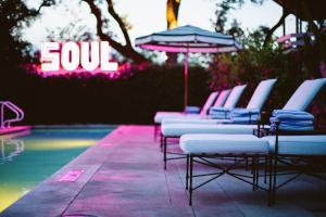 a row of chairs and an umbrella next to a swimming pool at Hotel Saint Cecilia in Austin