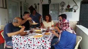 un grupo de personas sentadas alrededor de una mesa comiendo comida en Ekolojik Güney Köy Pembe Köşk en Balçıklı