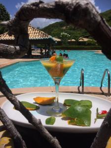 a drink sitting on a plate next to a pool at Pousada do Forte in Barra do Cunhau