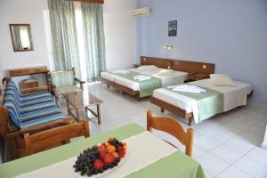 una camera d'albergo con due letti e un tavolo con un cesto di frutta di Maritime a Kremasti