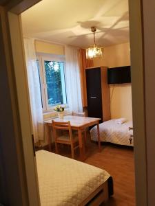 Habitación con mesa y dormitorio con cama. en Noclegi u Mai en Olsztyn