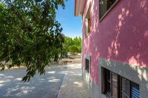 um edifício rosa com uma árvore ao lado de uma rua em Le Jardin Lisbon em Lisboa