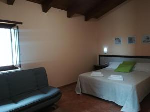 a bedroom with a bed and a couch and a window at Agriturismo I Tre Ulivi in Paternopoli