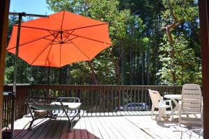 a patio with a table and chairs and an orange umbrella at Gabriola Central B&B in Gabriola