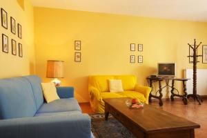 ヴェルバーニアにあるAppartamento Le Roseの青いソファと黄色の壁が特徴のリビングルーム