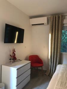 a bedroom with a white dresser and a red chair at Villa hortensia in Carpentras